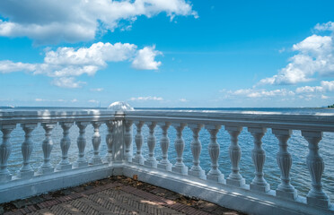 A curly marble parapet fence on the seashore against a background of clouds.