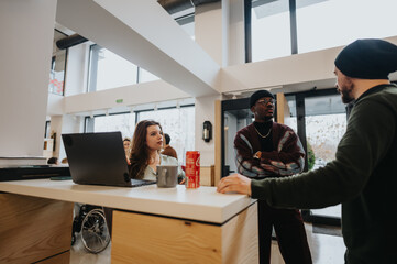 A multi-ethnic team engages in a collaborative discussion at a modern workspace with laptops and mugs, showcasing teamwork and casual business environment.