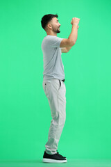 Fototapeta na wymiar A man, full-length, on a green background, with his hands raised
