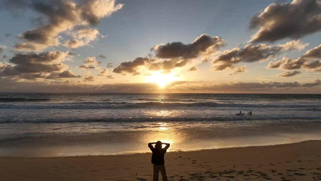 Chica viendo la puesta de sol en la playa