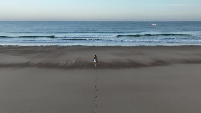 Chica paseando por la arena donde va dejando sus huellas