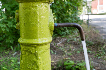 Antique working green colored street water spigot for hand-delivering drinking water running water.