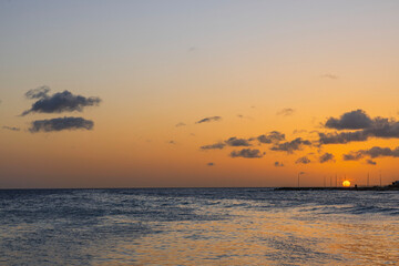 Fototapeta premium Captivating view of a orange sunset on island Curacao's horizon in the Caribbean Sea.