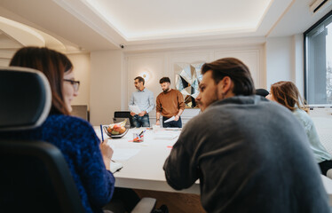 A collaborative modern office setup with a diverse team of professionals engaging in a casual business discussion.