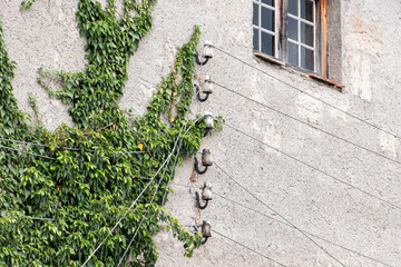 Fototapeta na wymiar Isolatoren einer Telefonleitung an alter Fassade