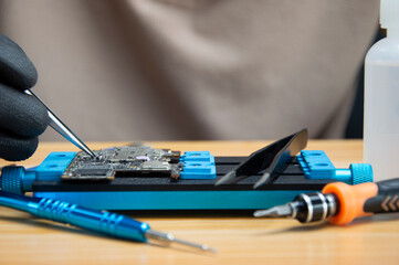 Technician is repairing Smartphone motherboard, circuit repair