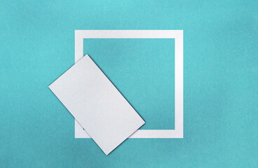White square on blue paper texture, blank page in foreground. Vivid colour background for your objects with frame. Plain graphics element for further work