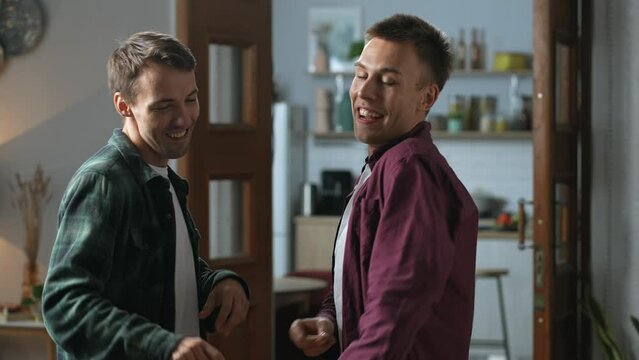 Carefree male couple celebrating their achievements celebrating moving into a new apartment, happily dancing together. They are full of joy and excitement to begin new chapter of their life.4k footage