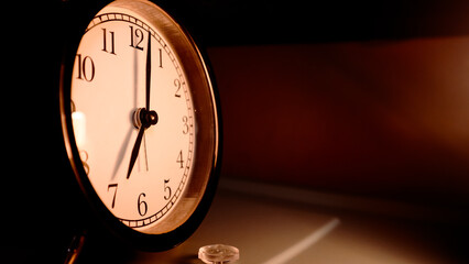 An alarm clock indicates seven o'clock.
