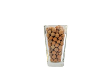 Leca clay balls artfully arranged in a transparent glass vase on white isolated background