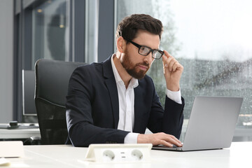 Man working on laptop at white desk in office