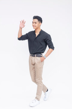Cheerful Filipino male in casual attire posing with a friendly wave while walking, isolated on a white background.