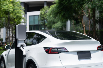 EV electric car charging in green sustainable city outdoor garden in summer. Urban sustainability...