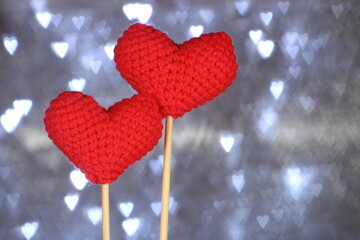 Valentine day concept idea. Two knitted red heart. Heart shaped bokeh on background. Selective focus. 
