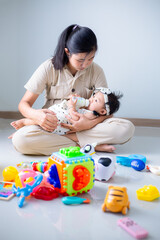 Mother and child playing with children's toys in the house,Mother and child are on the floor in the living room and play with her little child. The child likes to play very much. Around them are child