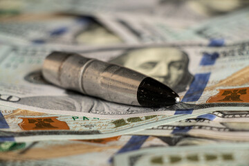 Hundred dollar bills and armor piercing bullet, finance and weapons