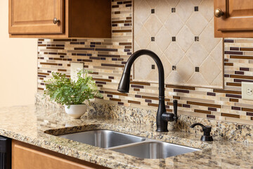 A kitchen faucet detail with wood cabinets, an oil rubbed bronze faucet, quartz countertop, and...