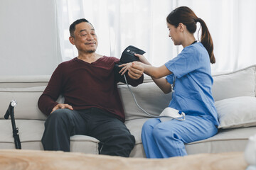 Caregiver nurse measuring blood pressure by using digital sphygmomanometer Senior patient at home....