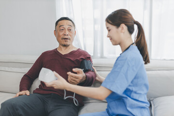 Caregiver nurse measuring blood pressure by using digital sphygmomanometer Senior patient at home. Caregiver nurse using medical device to measure blood pressure Senior patient