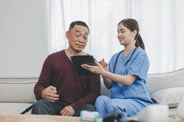 Nurse assisting her old patient at nursing home. Caregiver helping senior patient sit on sofa. Friendly female nurse talking with patient at nursing home