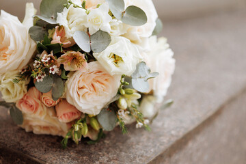 An elegant bouquet with blooming white roses and delicate blue flowers rests on a granite stone. Concept for wedding arrangements, floral designs, or romantic events.