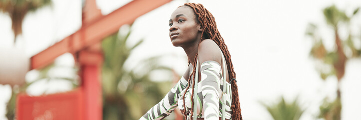 Gorgeous woman with African braids wearing top stands on the bridge, Panorama