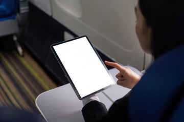 Woman traveler or passenger sits at the window seat, using his portable digital tablet touchpad during the flight. tablet white screen mockup - obrazy, fototapety, plakaty