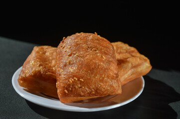 Odading or cube-shaped fried bread with a brown crispy outer skin and sprinkled with sesame seeds, the inside is empty and expands, so that it looks like a small pillow.