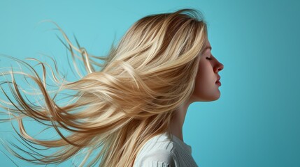 Beautiful Woman with Long  blond Hair fluttering in the wind on blue background with copy space. Beautiful healthy hair.