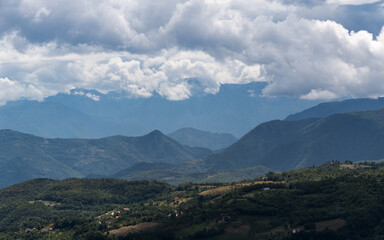 Fototapeta premium Mountain village against mountains in haze, countryside near Prozor in Bosnia and Herzegovina, mountain landscape