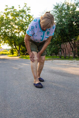 Old woman hurts her knee. Selective focus.