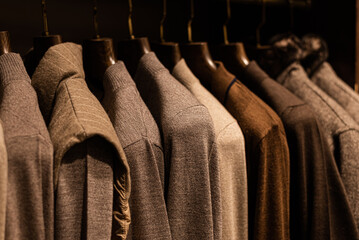 wardrobe with men's clothes in dark colors. jacket, down jacket, shirt. The clothes are neatly hung...