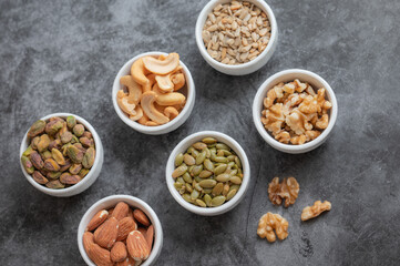 Obraz na płótnie Canvas Pistachios, almonds, cashews, pumpkin seeds, sunflower seeds, and walnuts on a gray counter top.