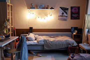 Background image of teens room interior with comfortable unmade bed and posters on wall