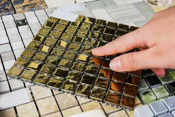 designer's hand choosing samples of interior stone material consists concrete tiles, quartz stones, artificial stones, graphic tile.