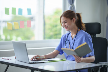 Attentive nurse in scrubs reviewing medical history or patient information on her laptop in office..