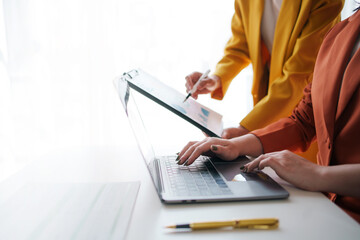 Close-up of a business meeting in progress with team members discussing over charts and a laptop, planning their corporate strategy.