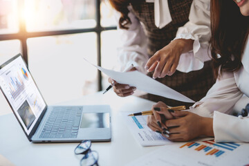 Close-up of a business meeting in progress with team members discussing over charts and a laptop, planning their corporate strategy.
