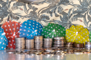 A pile of coins and parasols symbolizing money and exotic vacations.