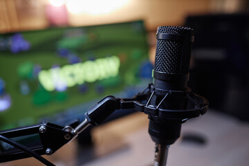 Close up of pro mic on stand with gaming screen in background, copy space