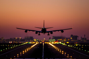 An airplane, landing at an airport at sunset.