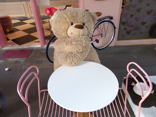 Orso giocattolo seduto in terrazza al tavolino del Bar. Italia