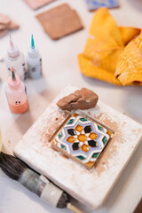 paints and brushes painting handmade tile in pottery studio