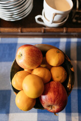 apples and lemons in a bowl on a table with a gingham tablecloth 