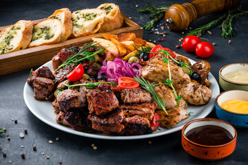 Restaurant beef and chicken barbecue with potato wedges, marinated red onion, fried mushrooms, garlic bread and sauces.