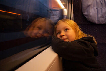 Girl child looks out the window sitting in the train