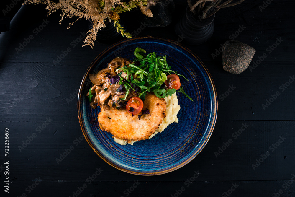 Wall mural fried breaded chicken fillet with mashed potatoes, mushrooms, arugula, lettuce and cherry tomatoes.