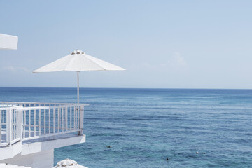 A large white umbrella on the background of the blue ocean. Leisure and travel concept with space for text