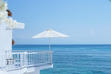 A large white umbrella on the balcony of the hotel with the ocean in the background. Leisure and...