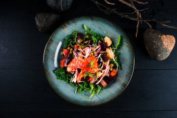 Fresh salad with salmon, beetroot, peas, cucumber, onion, carrot and arugula in plate.